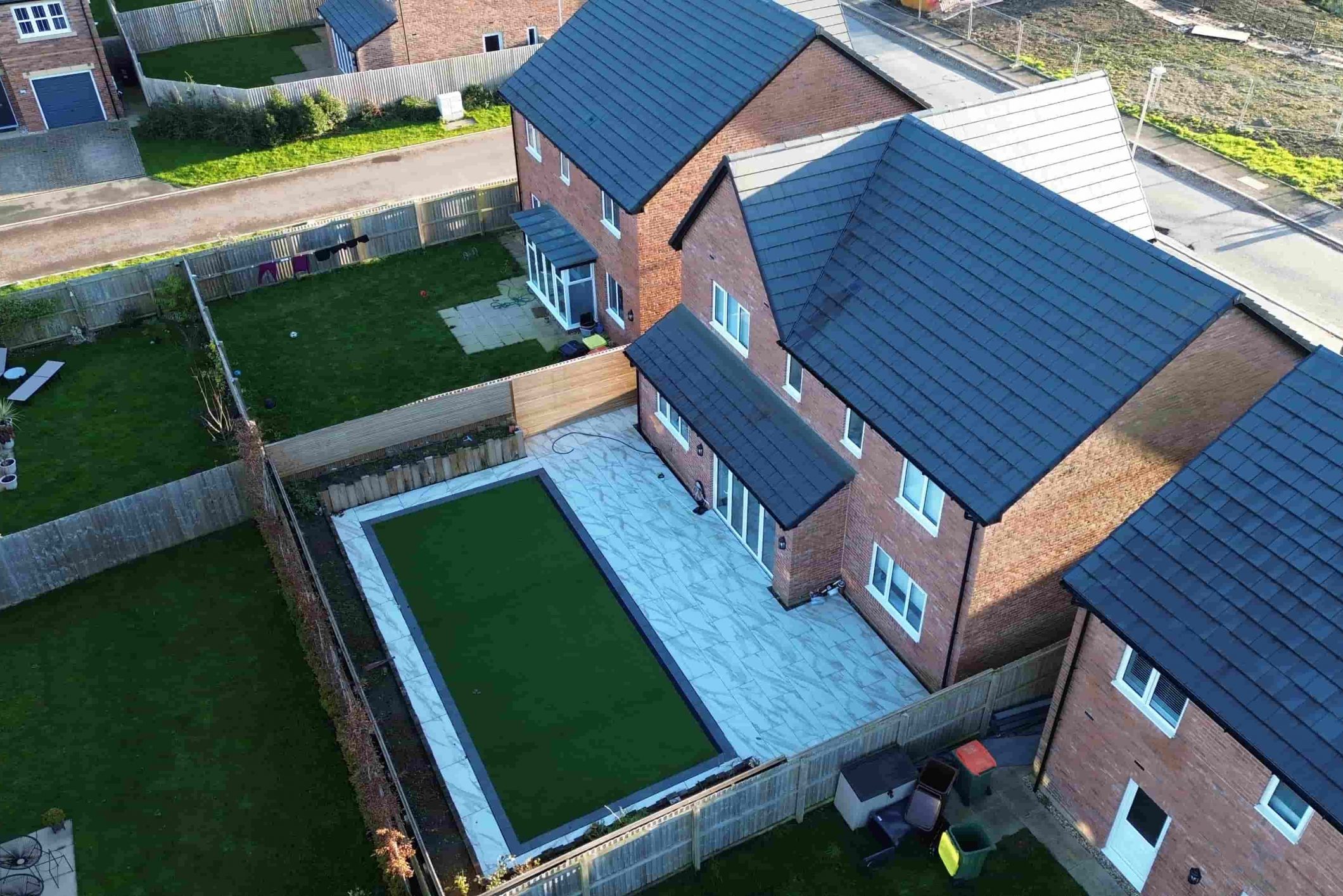 Top-down aerial view of artificial grass lawn with porcelain border in a Fulwood garden