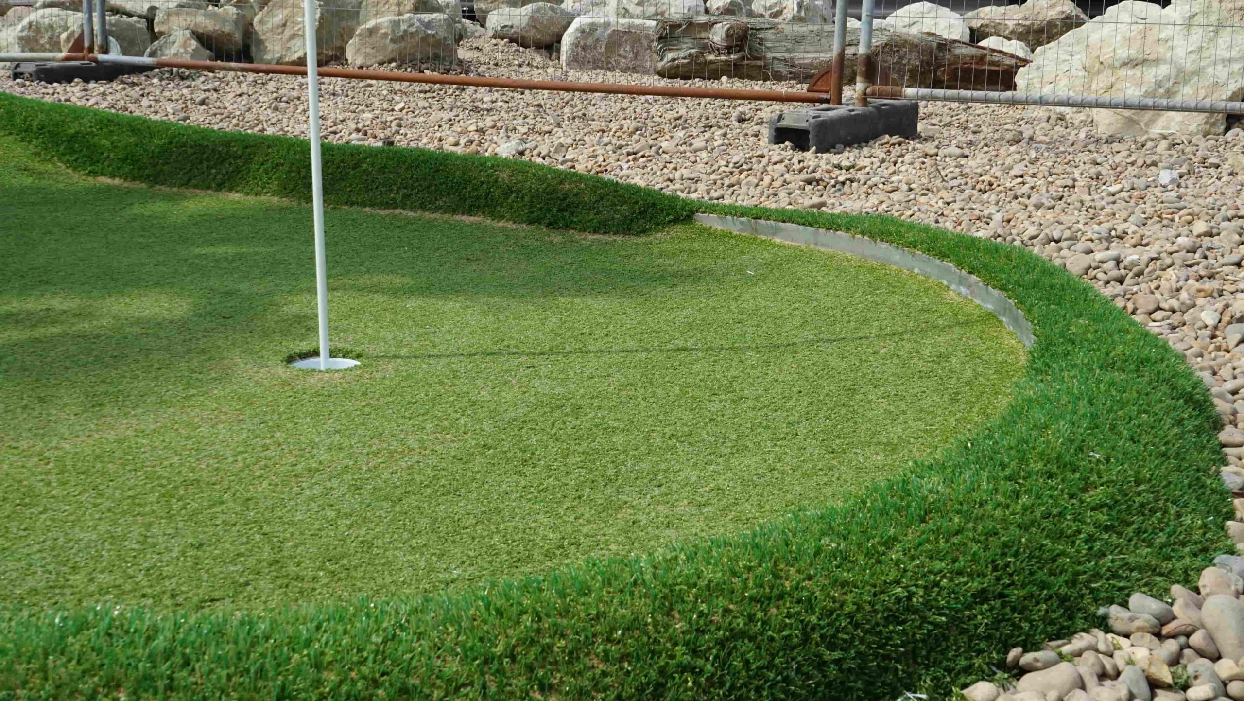Close-up of precisely cut artificial golf turf around concrete edging in Folkestone