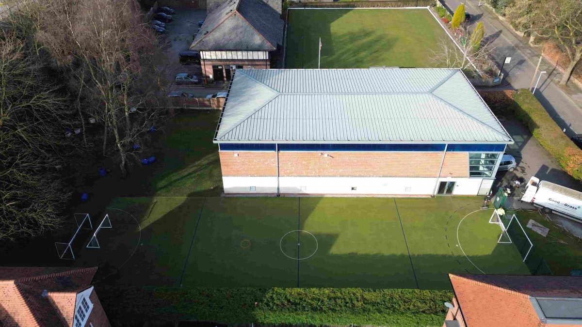 Aerial view of school artificial grass sports areas beside buildings in Wilmslow